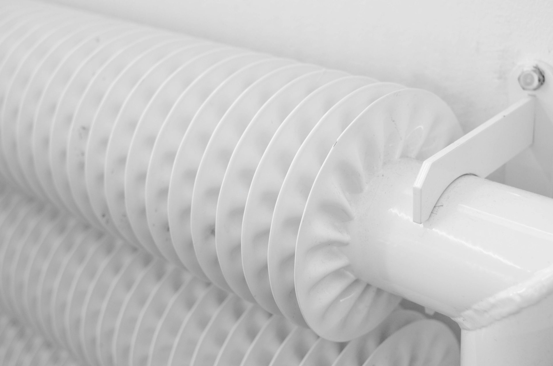 Système de radiateur à tubes en métal blanc avec tuyau pour chauffage industriel monté au mur avec crochet dans une pièce lumineuse à la maison